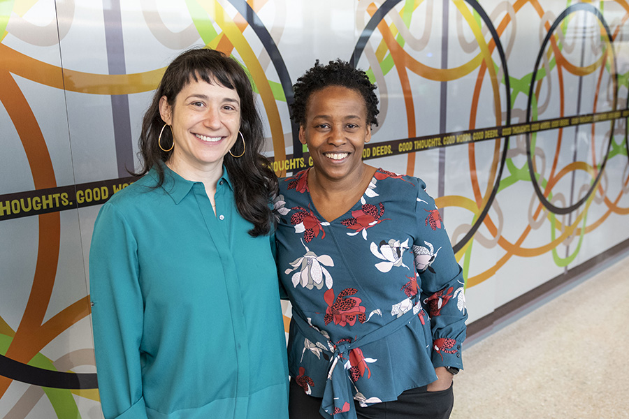 Elizabeth Chodos stands on the left with Stephanie Dinkins in front of a colorful mural