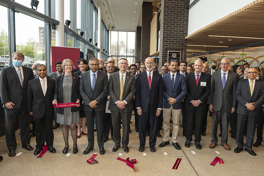 A group of corporate and government representatives stand in a line in front of a cut ribbon