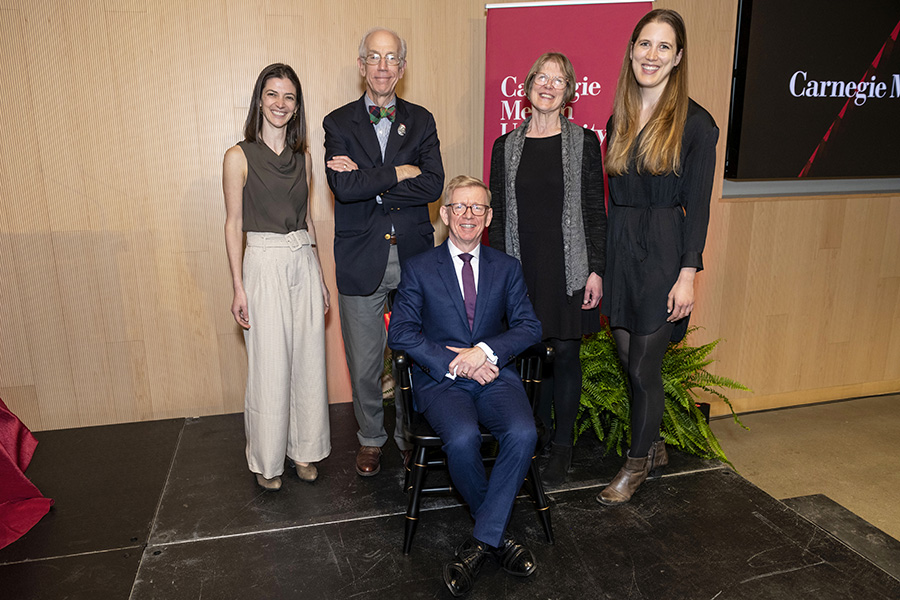 Dean Webster sits in a chair with four people behind him who are all smiling at the camera