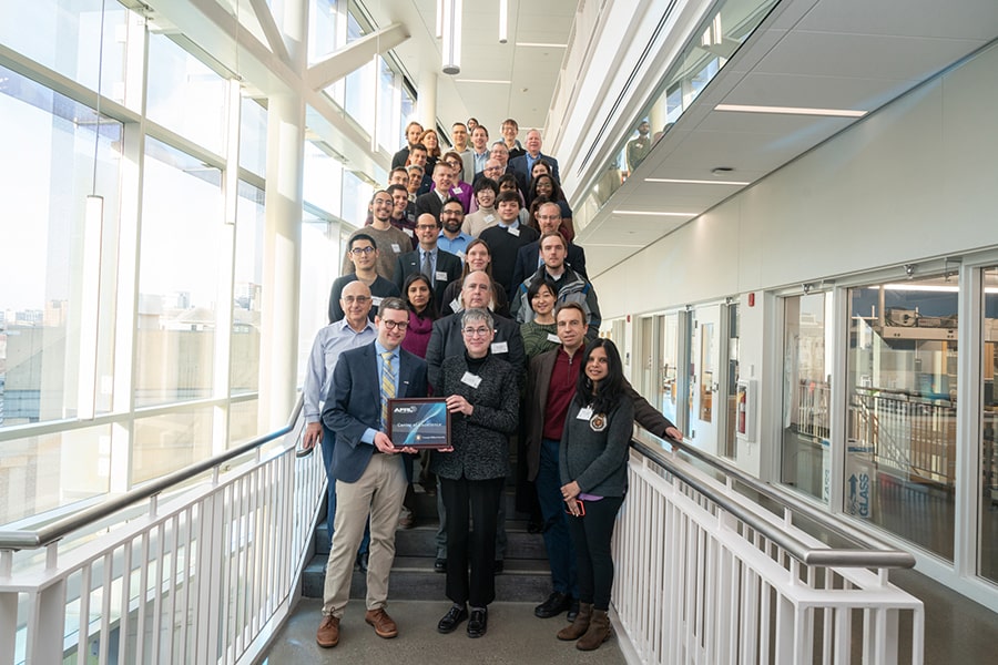 Group of researchers stand on the stairs in Hammerschlag Hall.